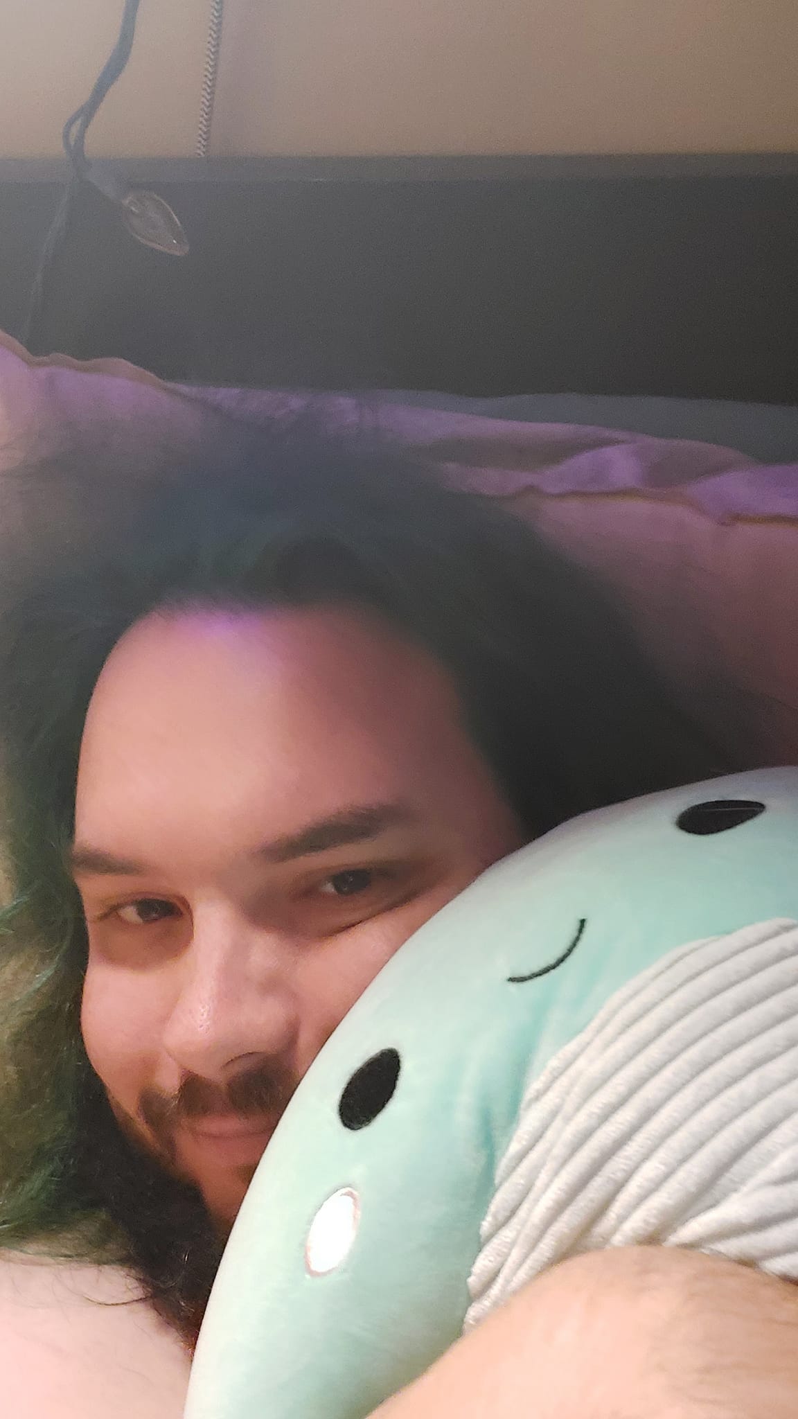 A man with green hair is holding a green Nessie Squishmallow, photo 2